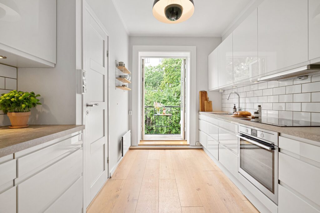 cuisine en longueur lumineuse aménagée avec meubles blancs et plan de travail bois